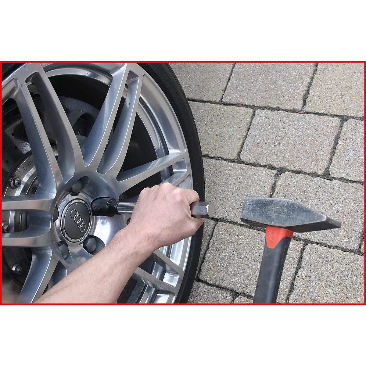 Eine Person montiert ein Rad. Der Reifen ist zur Hälfte zu sehen, daneben liegt ein Hammer.